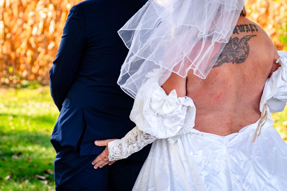 Bride in vintage-style lace dress with flowing veil against autumn background.