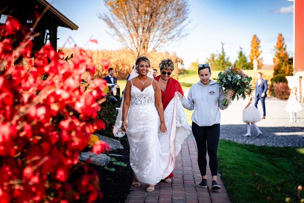 Wedding party walking outdoors with red autumn foliage and blue sky background.