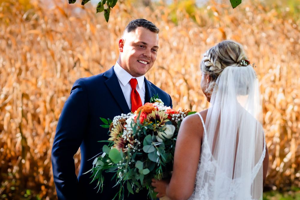 Wedding couple posing in front of golden cornfield with autumn colors.