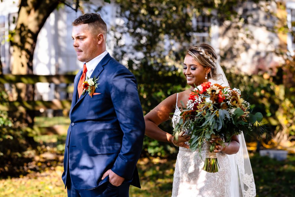 Wedding celebration group in navy and white attire gathered outdoors in golden fall setting.