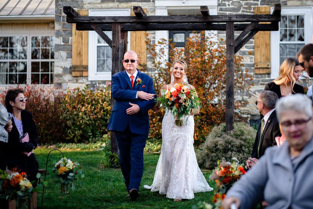 Wedding ceremony setup outdoors with white chairs and decorative elements at a rustic venue.