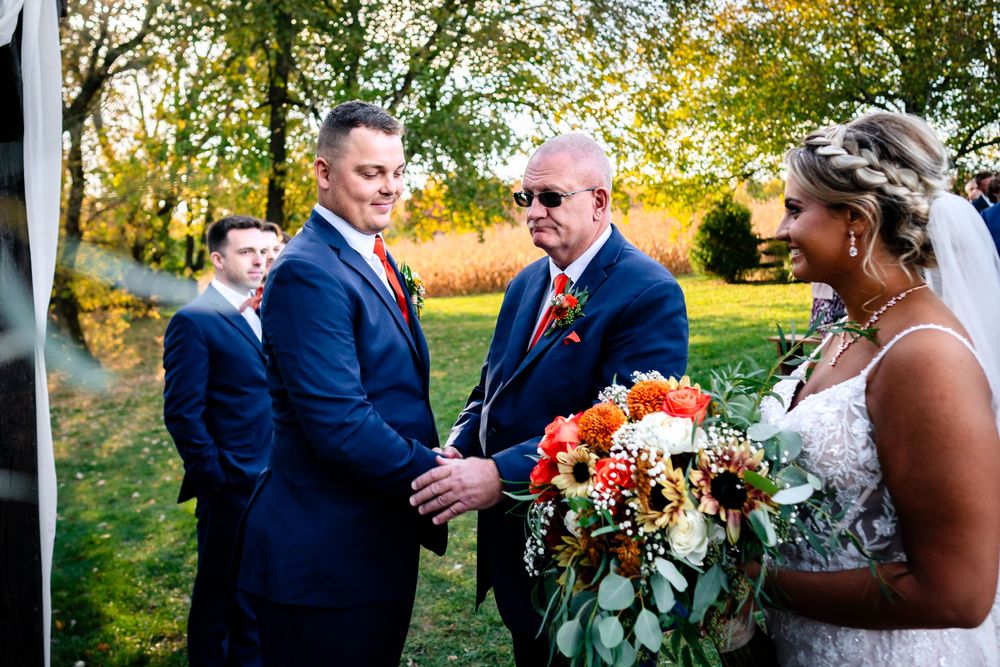 Wedding party posing outdoors during golden hour with autumn trees in the background.