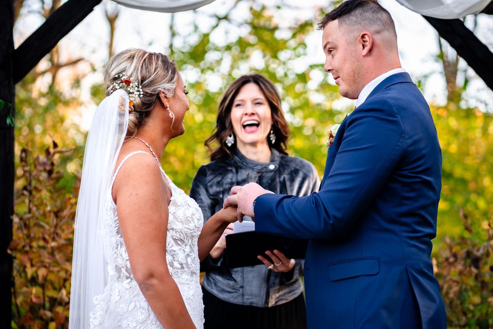 Emotional wedding ceremony moments captured under a decorated arch with autumn foliage.