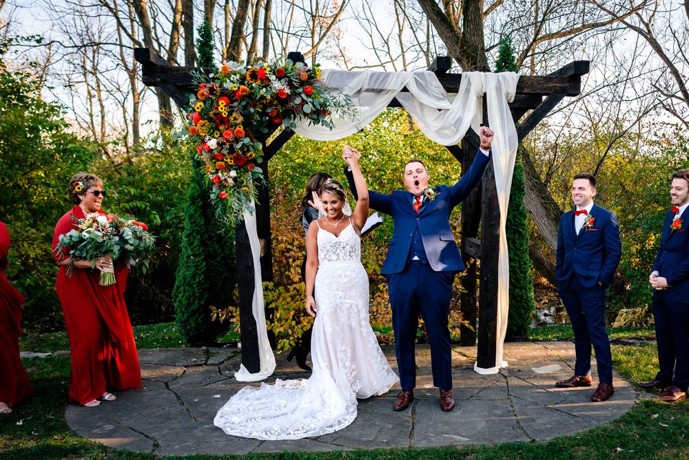 An outdoor wedding ceremony setup with white chairs arranged in rows under autumn trees.