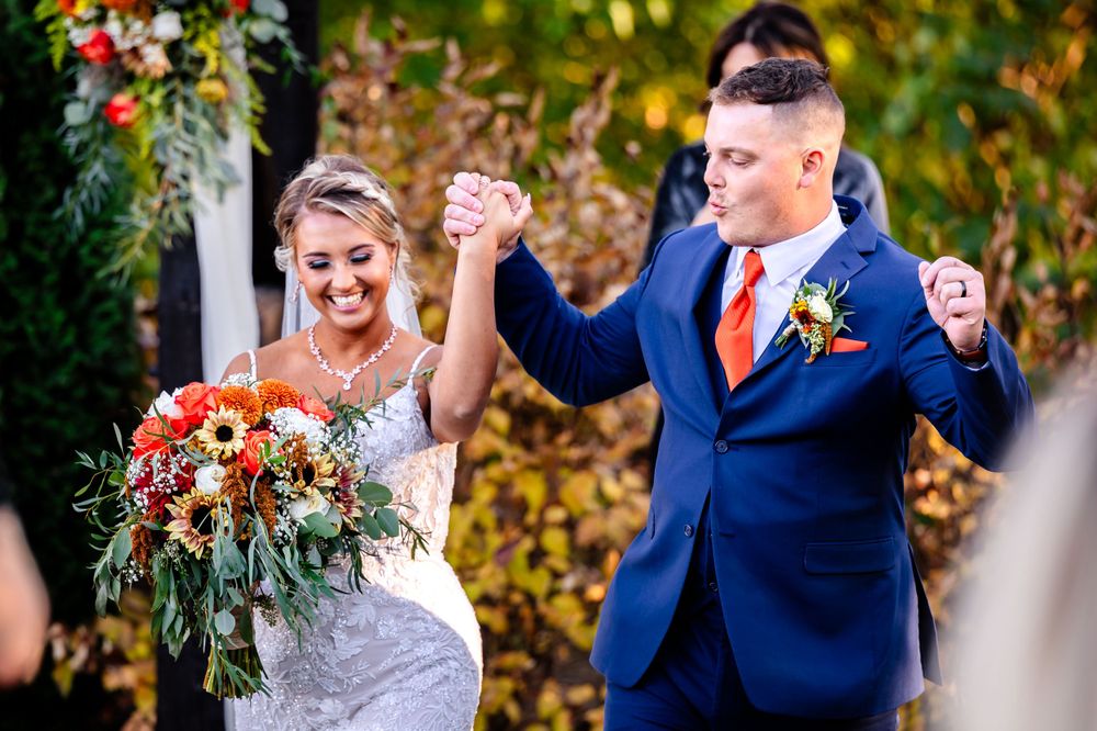 A fall wedding celebration with vibrant orange and red floral arrangements.