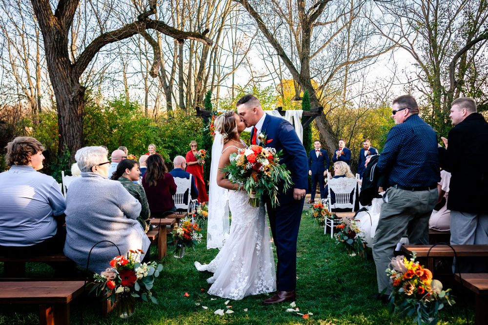 Wedding guests seated outdoors for a ceremony with bare trees in the background.