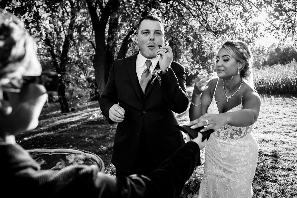 A black and white wedding photo capturing candid moments during an outdoor celebration.