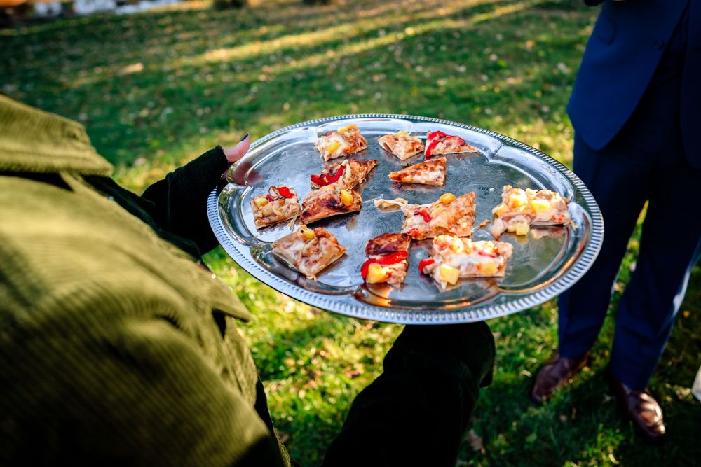 Appetizer plates being served at an outdoor wedding reception on the lawn.