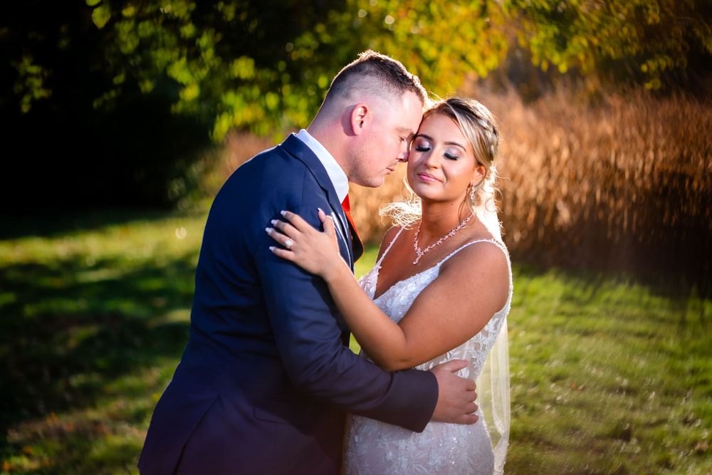 A romantic moment captured during golden hour at an autumn wedding.