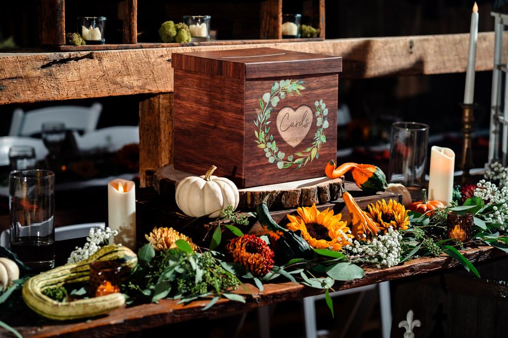 Rustic barn wedding reception table decorated with autumn pumpkins and greenery.