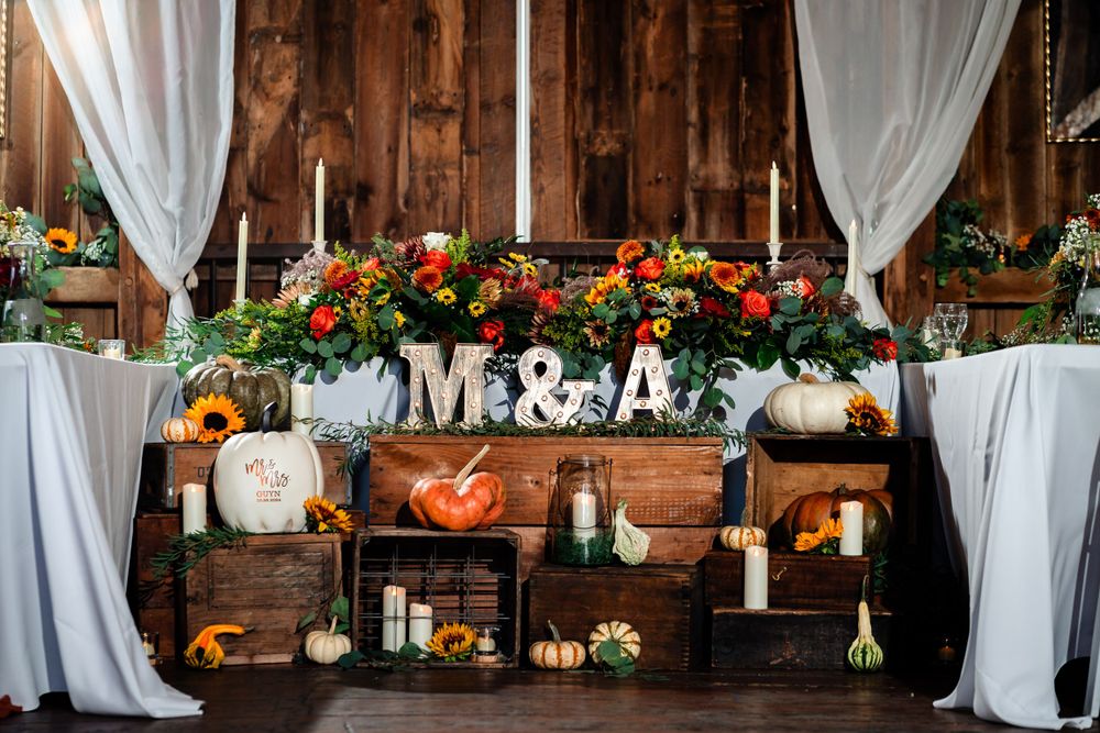Elegant barn venue with white drapes and floral decorations along wooden beams.
