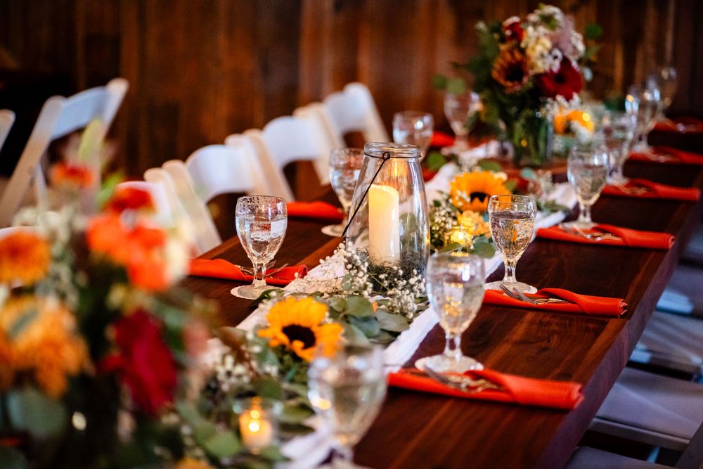 Wedding reception table settings with red napkins and colorful floral centerpieces.