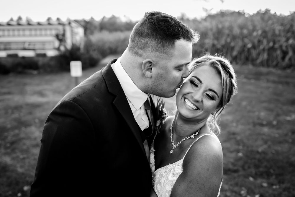 Wedding couple embracing in a rustic outdoor setting during golden hour.