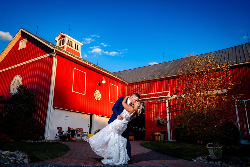 Red barn wedding venue under bright blue skies with dramatic architectural angles.