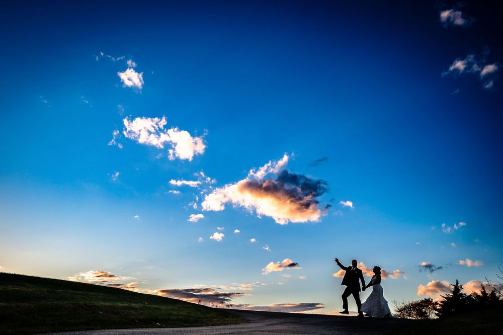 Dramatic sunset silhouettes against vibrant blue sky with scattered clouds.