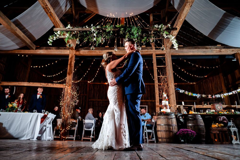 Rustic barn reception venue decorated with string lights and wooden beams.