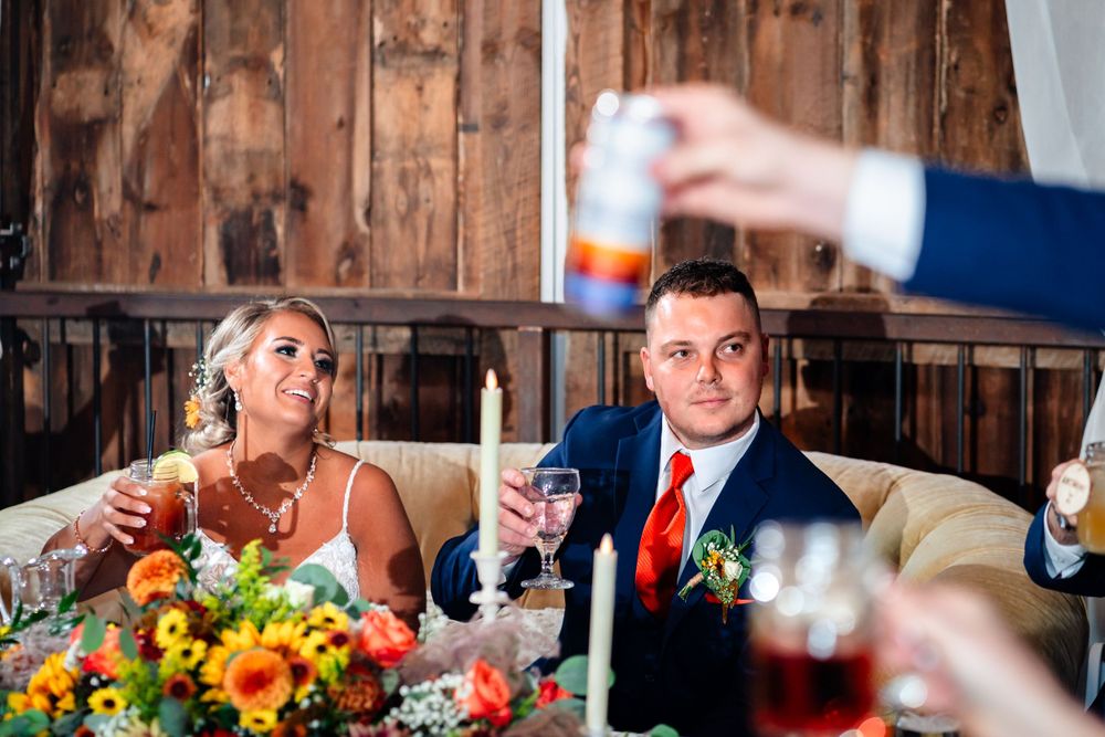 Wedding reception dinner setup in rustic barn with autumn floral centerpieces.
