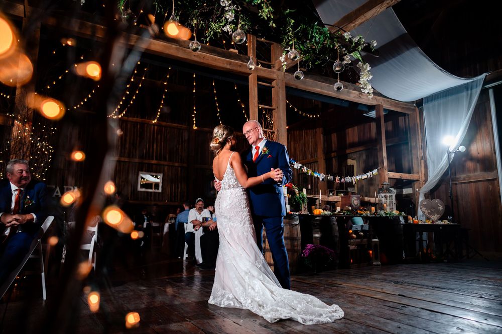 Couple shares first dance under twinkling lights in rustic barn venue.