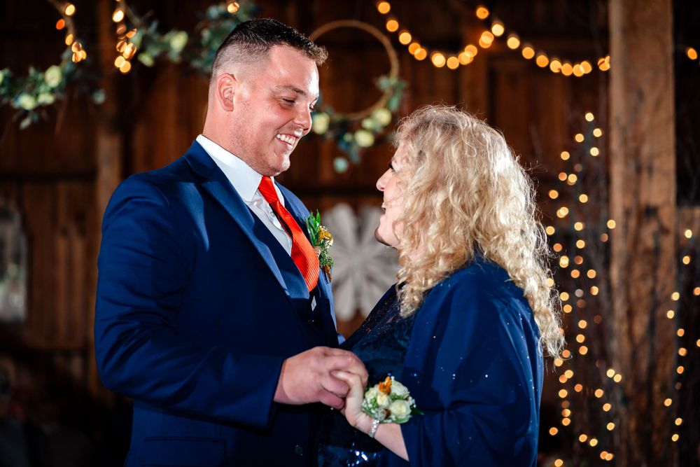 Couple shares intimate moment under twinkling lights at evening celebration.