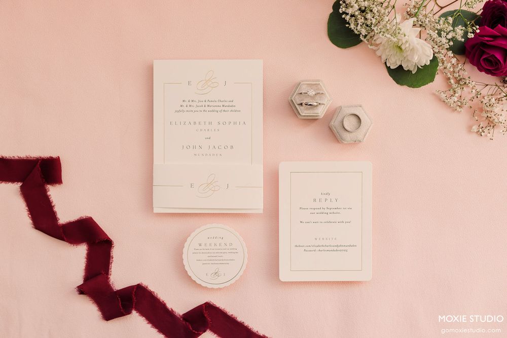 Elegant wedding invitation suite with burgundy velvet ribbon and blush pink details on a light pink background.