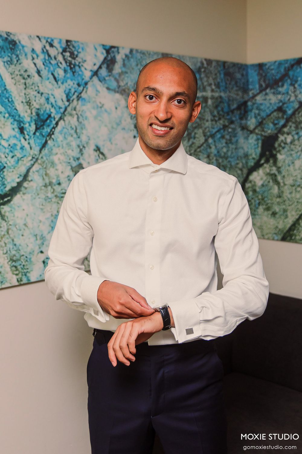 Professional studio portraits of a person in a white dress shirt and navy pants against a blue abstract art background.