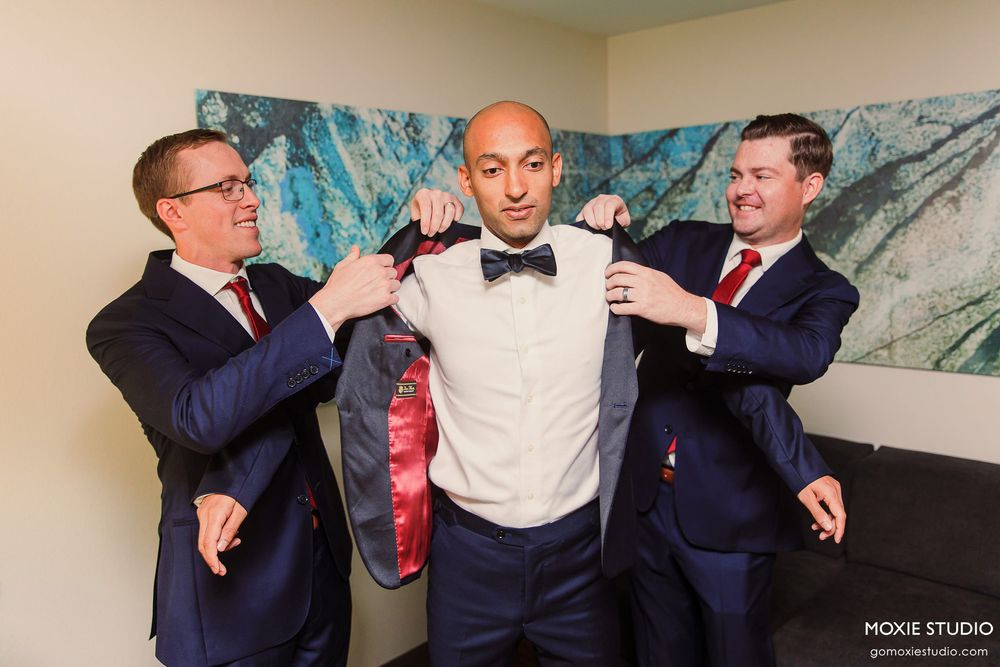 Groomsmen in navy suits sharing playful moments during wedding preparations.