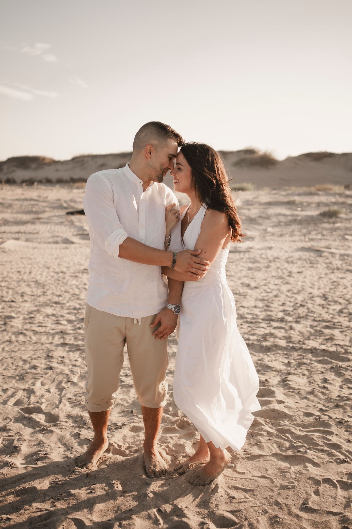 Cinematic wide shot of an engaged couple walking on the sand dunes during a sunset beach session in Venice Lido.