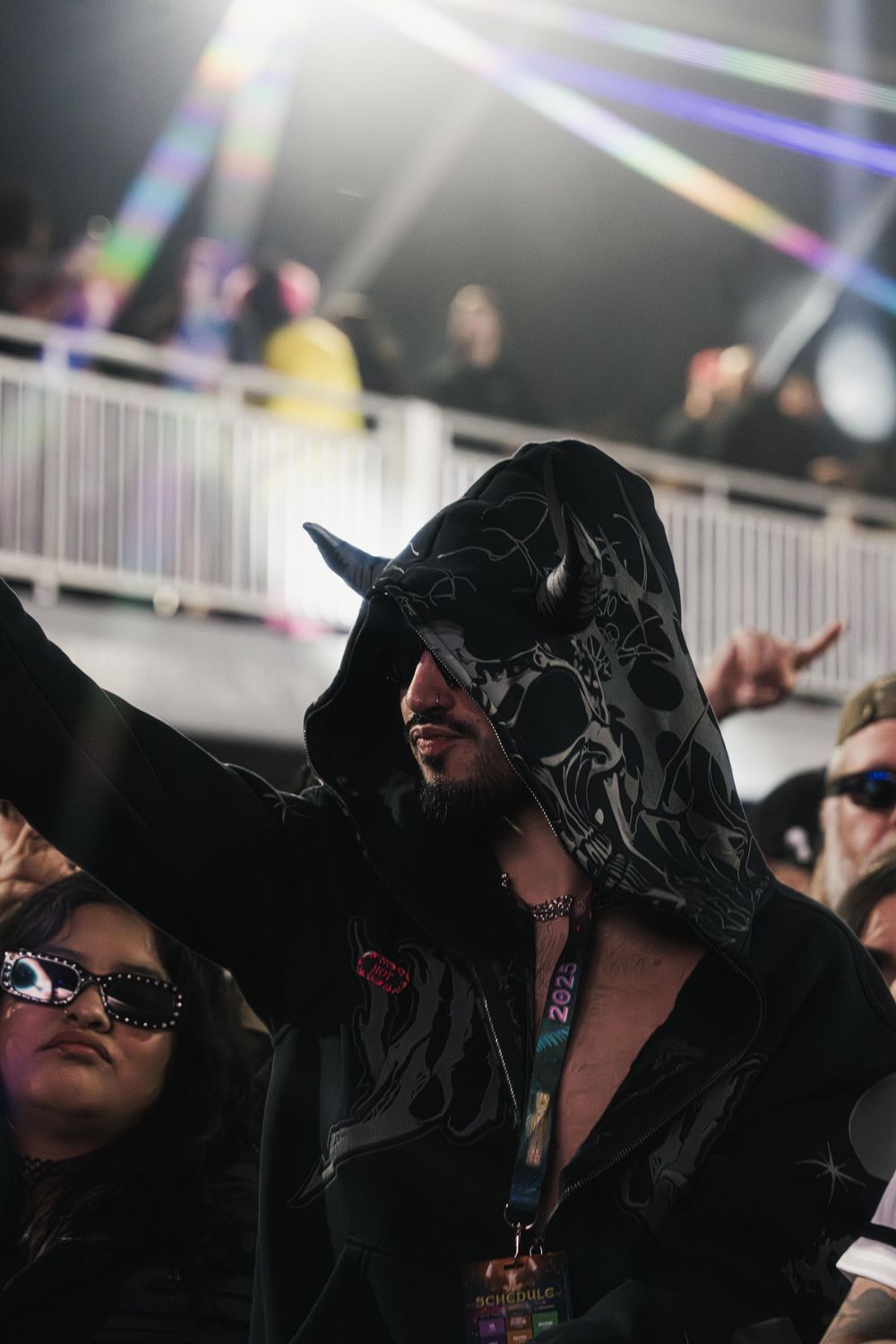 People wearing black hooded outfits and sunglasses sit together at what appears to be an event or gathering.