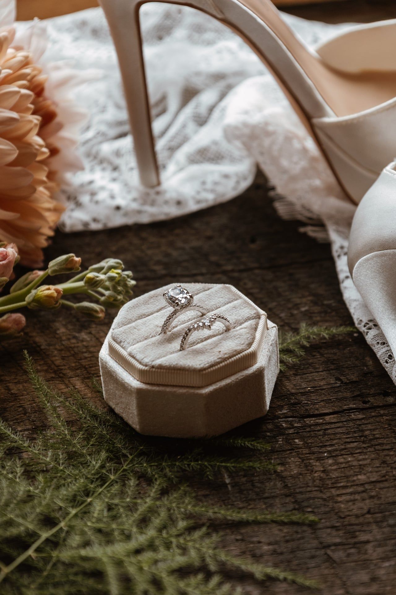 Wedding rings displayed on white cushion with delicate florals and greenery.