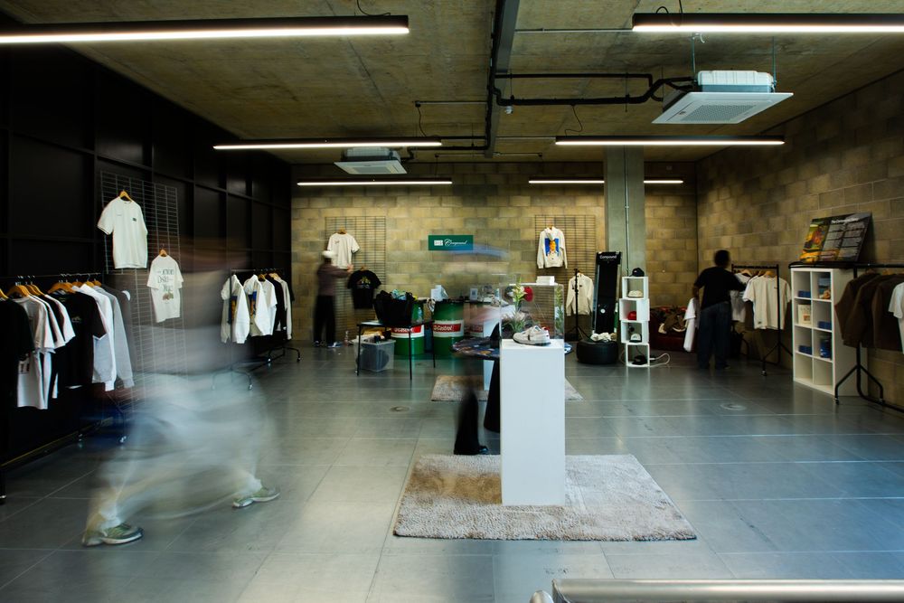 Modern retail store interior with clothing racks, display pedestals, and blurred shoppers under industrial lighting.