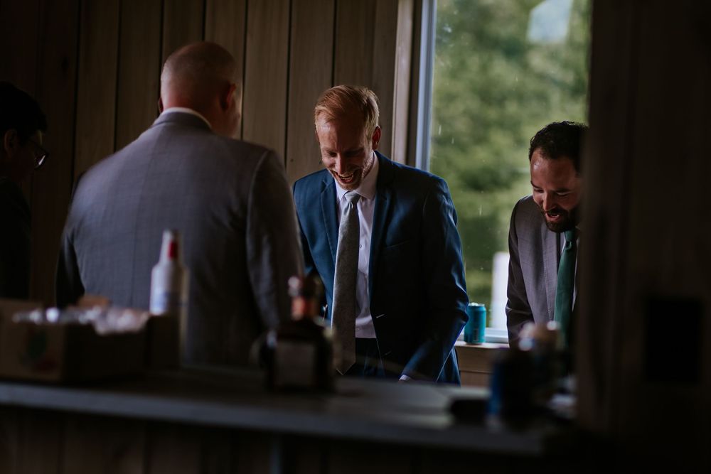 Wedding party gathered near windows in a dark wood-paneled room.