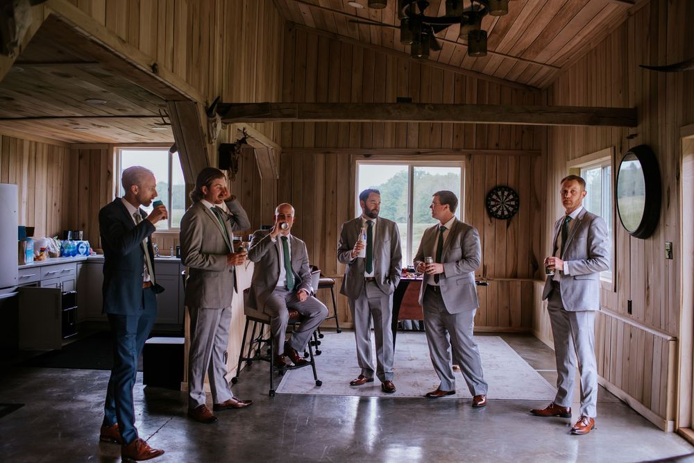 Wide panoramic view of rustic wooden interior with guests gathering for an event.