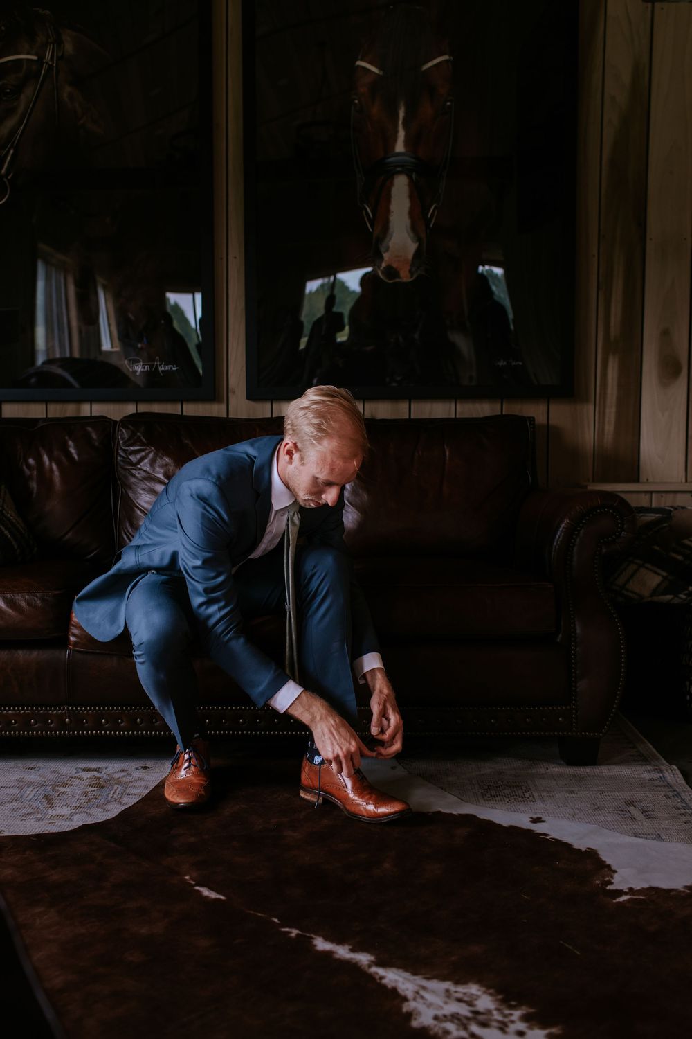 Person in blue suit crouches down on dark wooden floor in dramatic lighting.