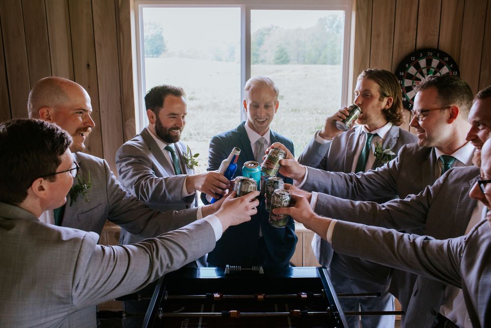 Groomsmen toasting with drinks in rustic wooden room.