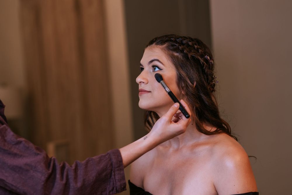 Wedding preparation scene with makeup application in soft natural light.