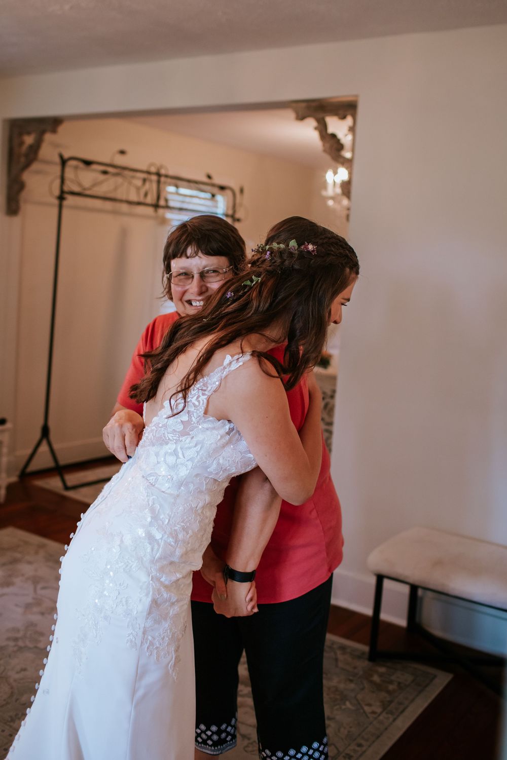 Wedding party sharing hugs and embraces in bright indoor setting.