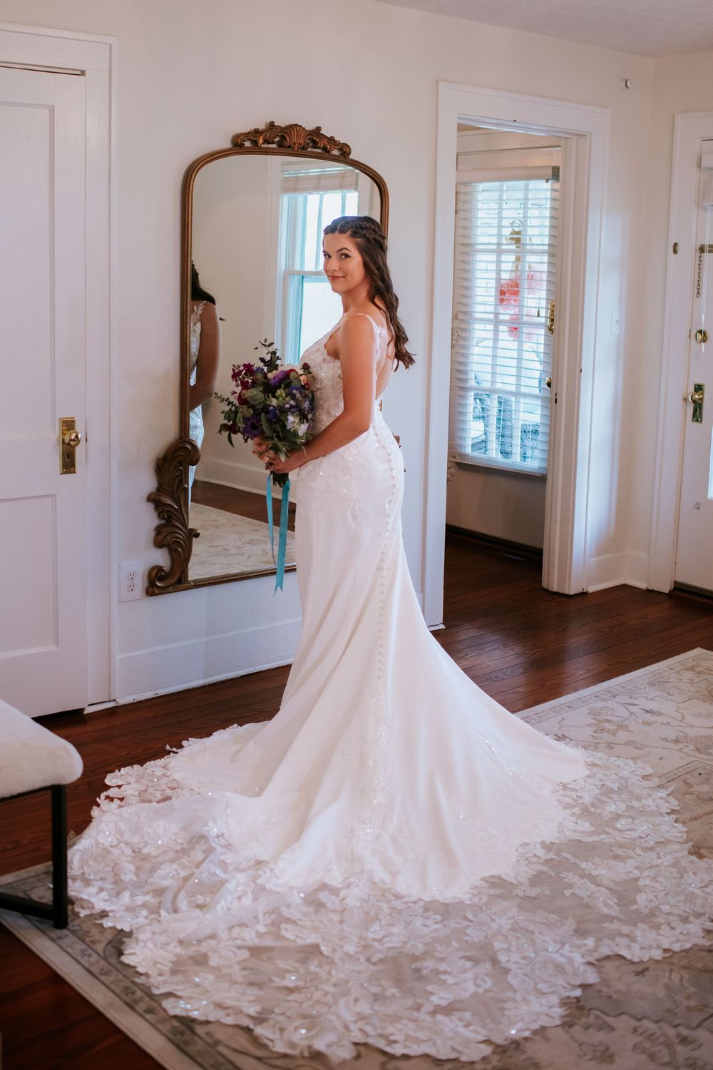 Stunning white wedding gown with long lace train displayed in elegant room.