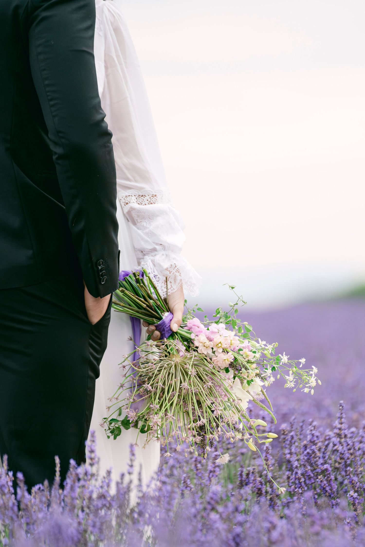 Mariés dans un champ de lavande en Provence, bouquet sauvage, moment tendre et naturel.