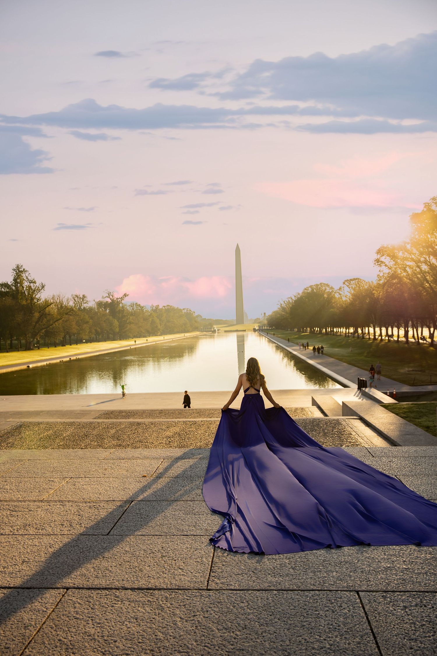 A flowing navy blue dress billows dramatically against the backdrop of the Washington Monument at sunset. Flying Dress Photoshoot