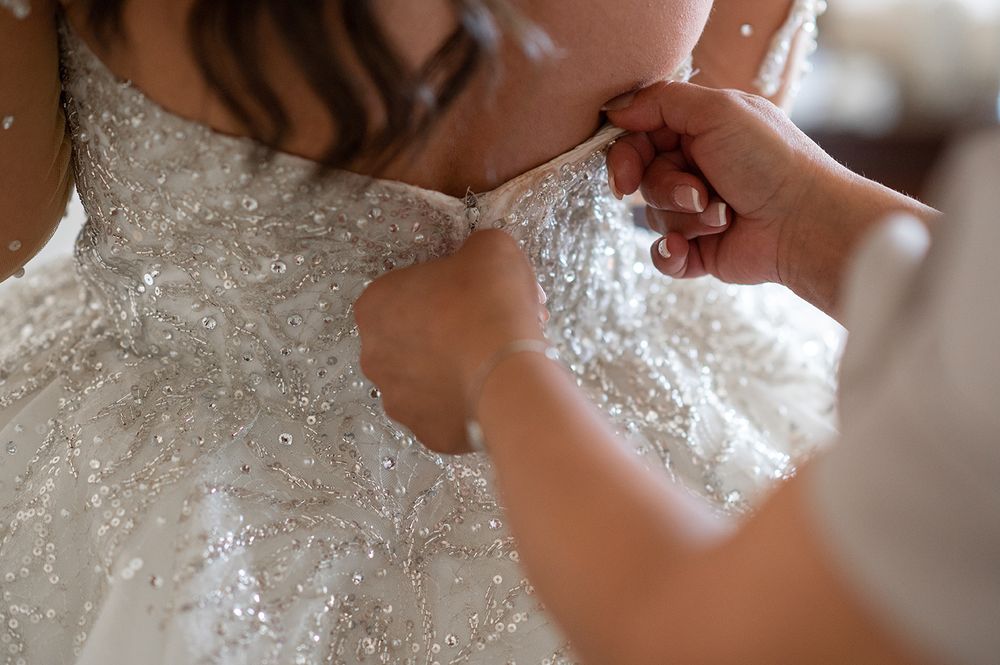 Close-up detail shot of intricate beading and lace work on a white wedding dress.