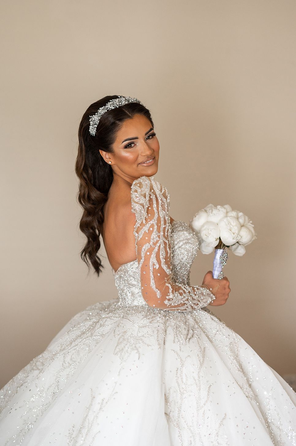 A stunning white ball gown wedding dress with intricate lace details and long sleeves shown from different angles.