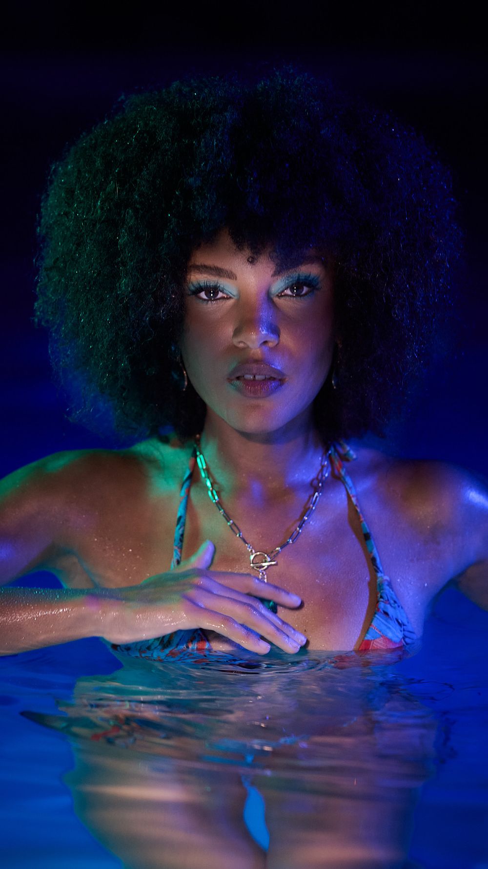 Underwater portrait series with blue lighting showing a model with natural hair in artistic swimming poses.