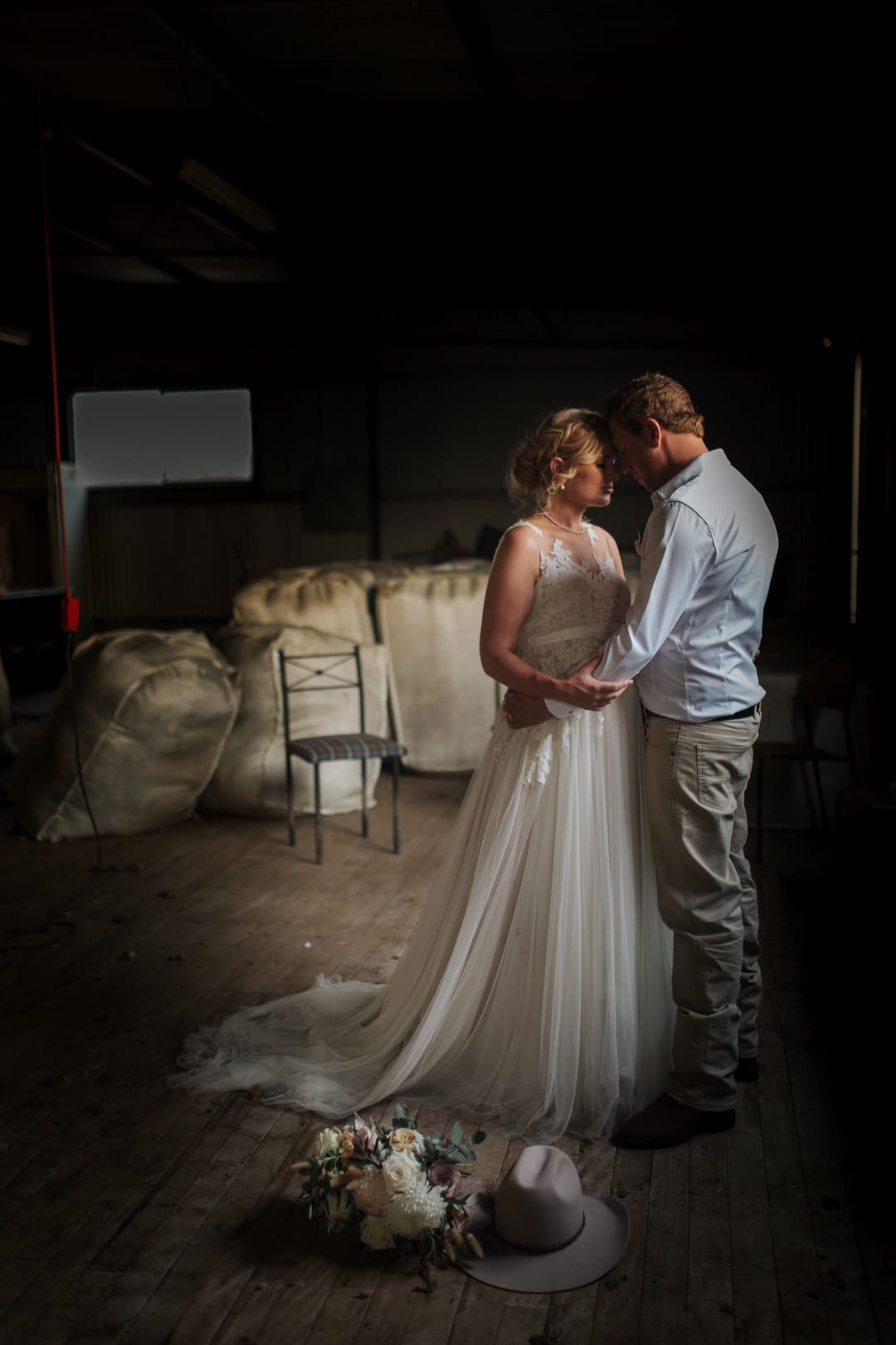 A bride and groom on their wedding day holding each other in a quite moment at the woolshed
