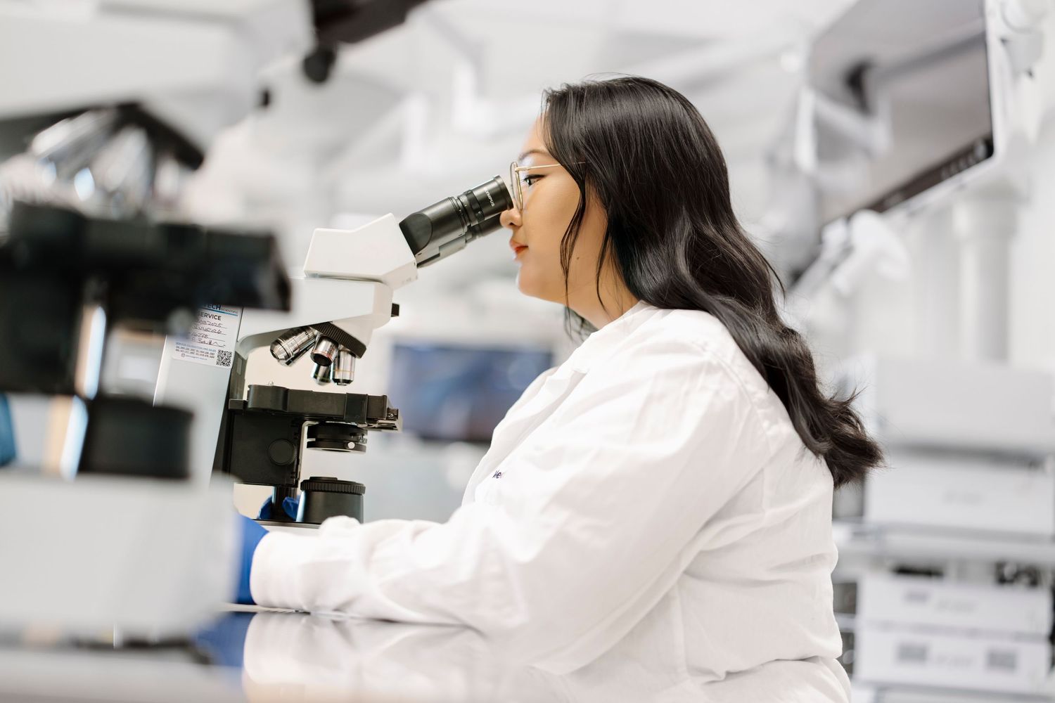 Laboratory technician in white coat uses scientific equipment in modern research facility.