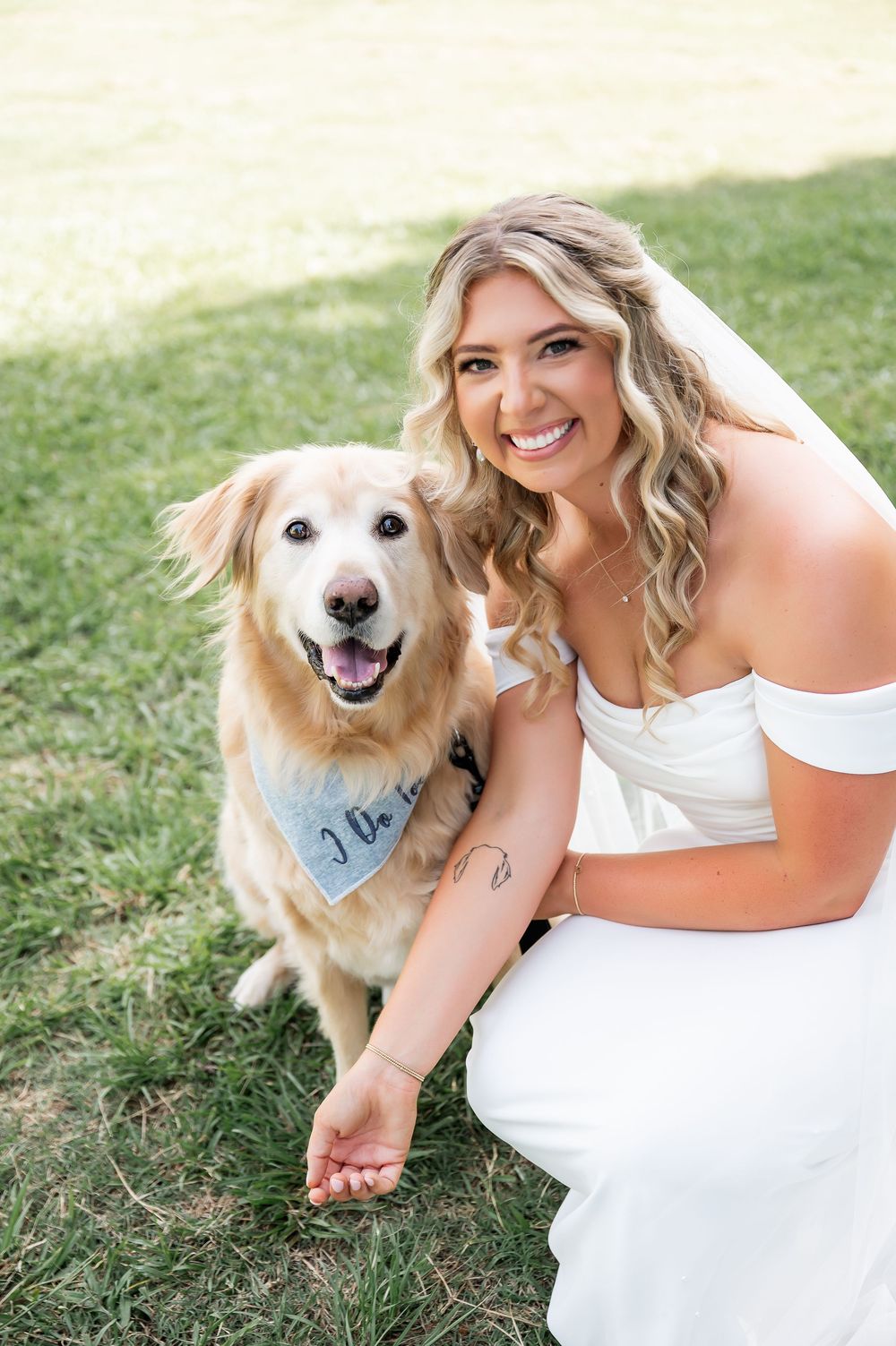 Happy golden retriever joins bride for wedding photos on grassy lawn.
