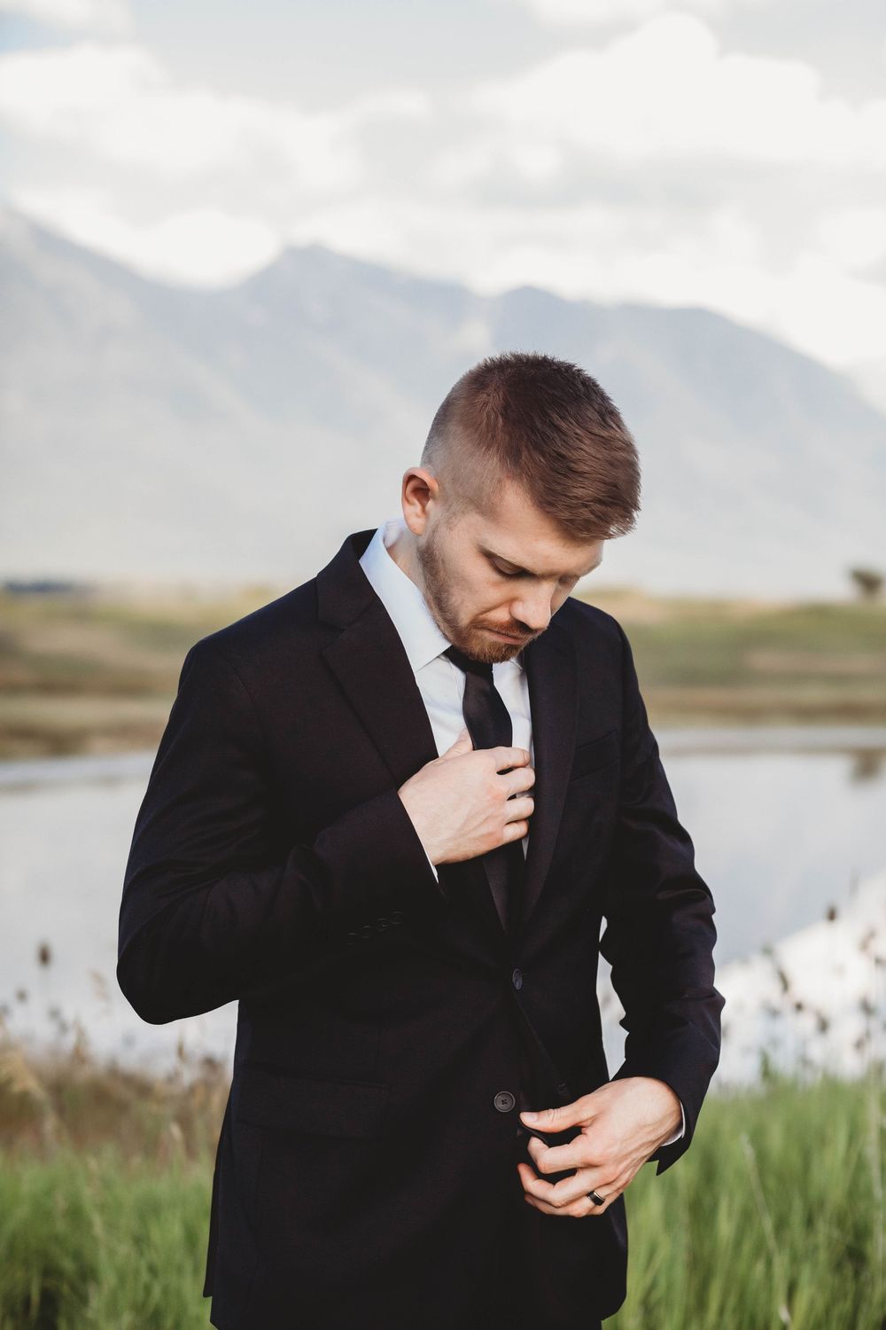 A series of emotional moments showing someone in a black suit standing near a lake with mountains in the background.