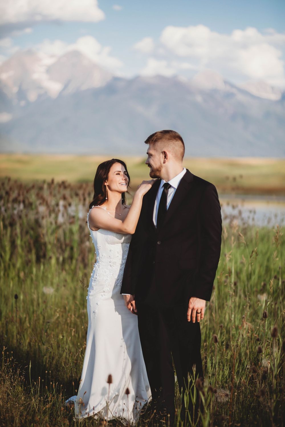 A romantic wedding portrait with mountain peaks and a lake in the background.