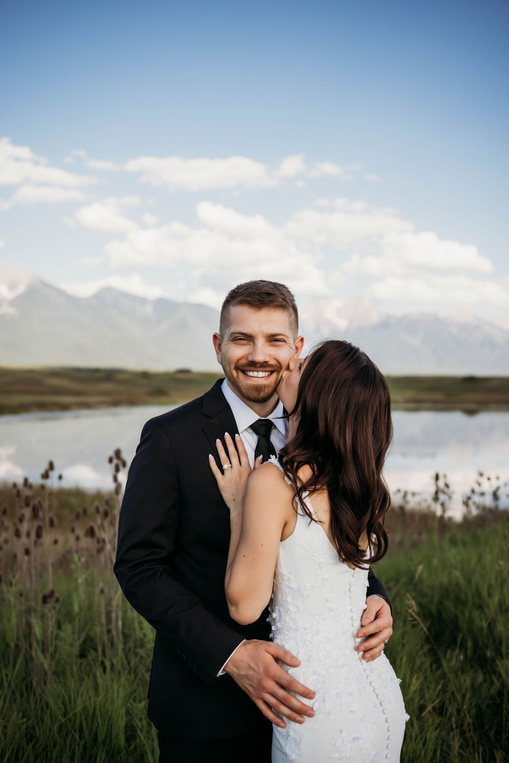 A romantic wedding portrait with mountains and a lake creating a stunning natural backdrop.
