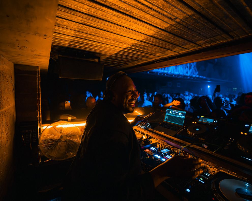 Dimly lit nightclub interior with wooden ceiling beams and blue ambient lighting creating a moody atmosphere.