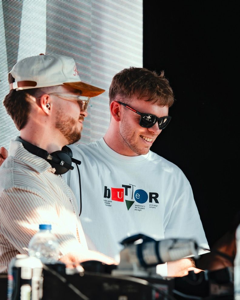 A group of people wearing white shirts and baseball caps work together at what appears to be a racing event.
